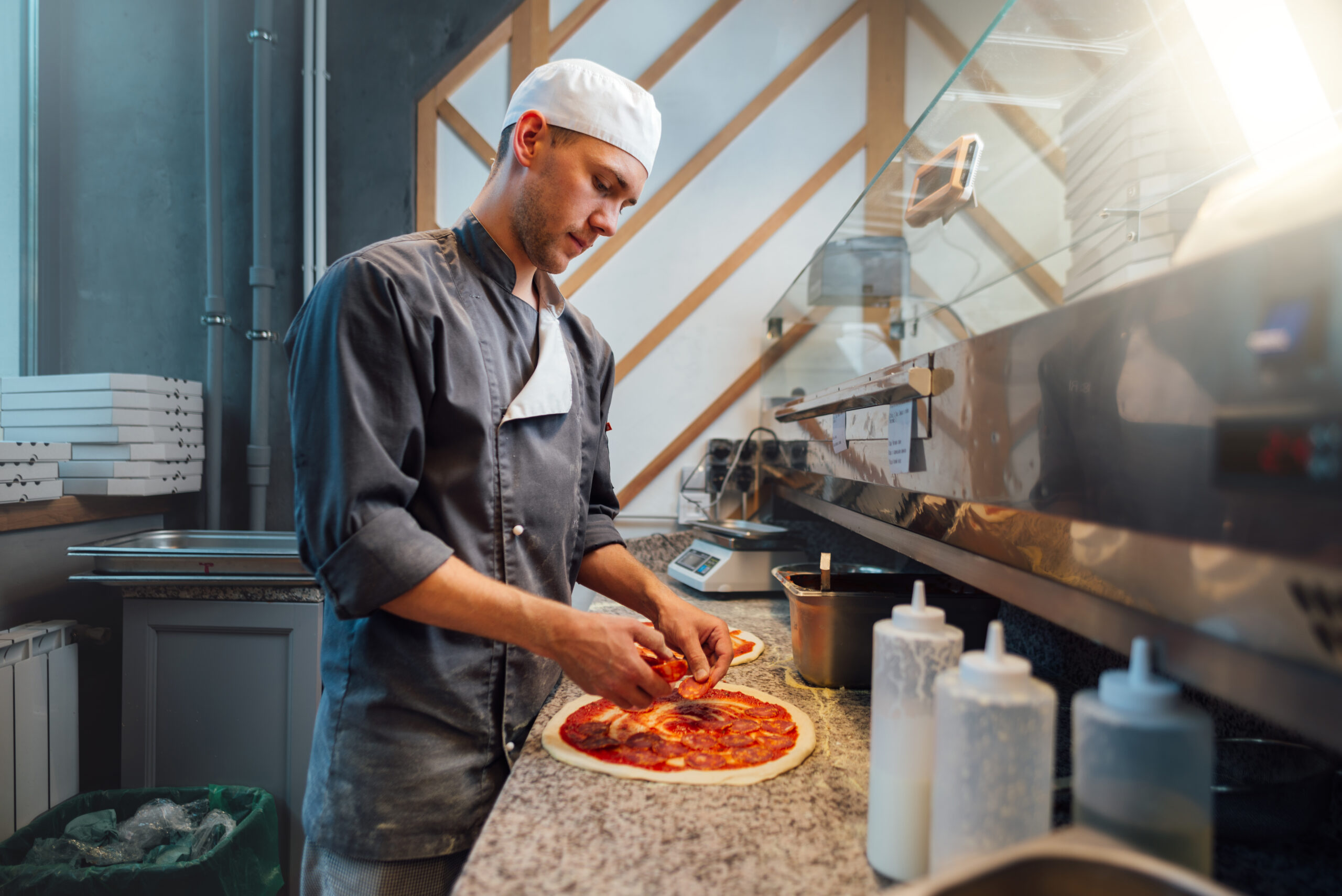 Cook prepares pizza. Catering kitchen work.